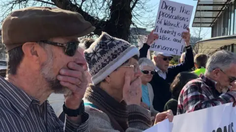 Australian Broadcasting Corporation Protestors cover their mouths at a demonstration protesting the prosecution of Bernard Collaery