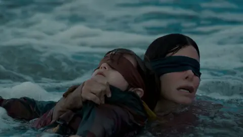 Saeed Adyani/Netflix Sandra Bullock and child in river