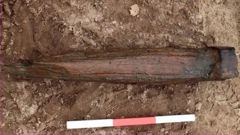 Cotswold Archaeology The wooden axle fragment was modified and reused as a stake