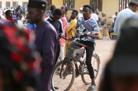 Reuters A man playing a guitar on a bicycle as he waits to vote in Yola, Nigeria - Saturday 25 February 20233