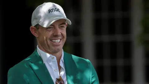 Rory McIlroy smiles as he talks to Augusta officials on his return to the Masters