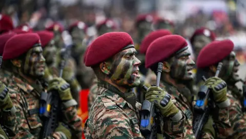 Getty Images Gorkha Rifles Regimental Center seen in red berets and camouflage as they hold up rifles during a march at Army Day Parade on January 15, 2024 in Lucknow