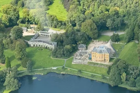 HCT An aerial view of Haining House in the Scottish Borders and the surrounding estate and homes with a loch in the foreground