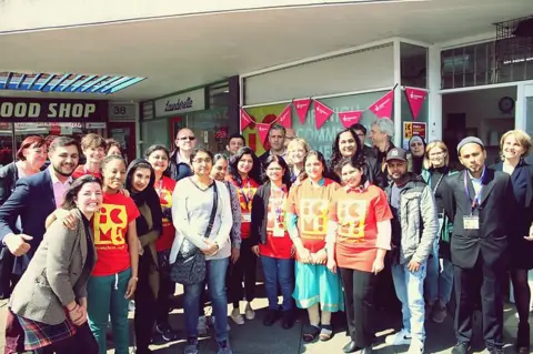 Contributed A large group of people stand in front of an office building, some are wearing red branded t-shirts with ICM on the front