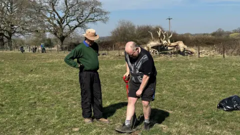 A council contractor helping a volunteer with planting a tree for the woodland memorial.