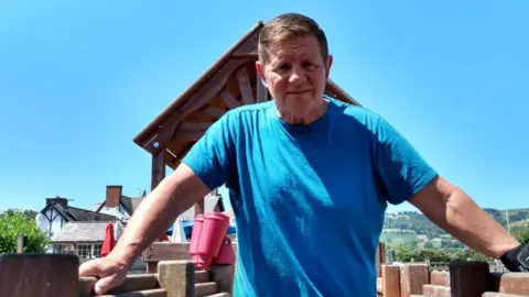 Gary Bulmer stood on the pub decking. He has brown hair, wearing a blue T-shirt and looking directly into the camera