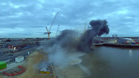 Sky Revolutions Smoke billowing up into the sky when a bomb exploded in Great Yarmouth. Yellow cranes can be seen in the background and an industrial estate on the other side of the river