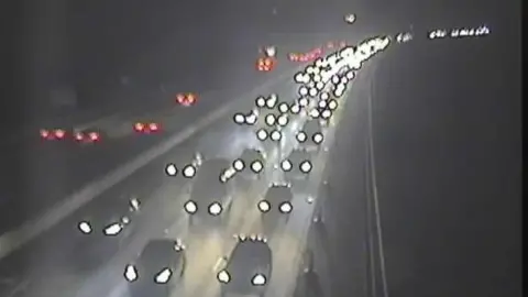 Cars are moving slowly on a motorway eastbound carriageway after a crash, with vehicles in all lanes seen for a while.