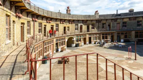 Getty Images A view of the inner circular shaped parade and courtyard area of the Fort. Windows overlook the area and people can be seen walking around an upper level.