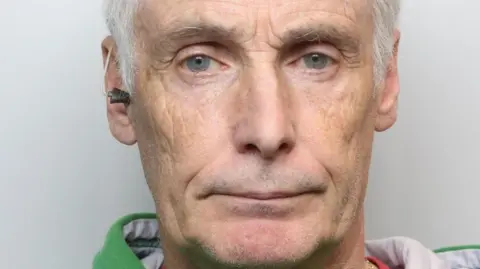 Alan Ellinson has craggy features, grey hair and a green shirt