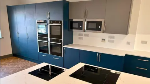 The Way The kitchen is bright and airy with blue cupboards and white surfaces.
