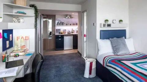 Study Inn/City of York Council A room with a desk on the left and a single bed on the right. In the back of the room is a kitchenette and a door leading to a small bathroom