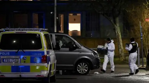 Reuters A forensics team gathers boxes outside of a school, and brings them towards a Swedish police van. It is nighttime