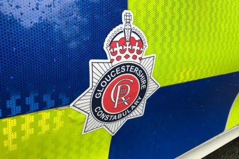 Image of the black, red and white Gloucestershire Constabulary crest on the side of a high viz police vehicle