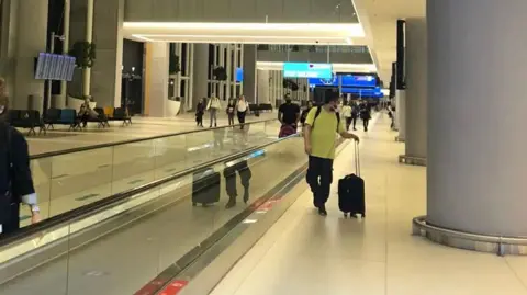 Garry Bolton A moving walkway at Istanbul airport, with people walking in both directions with luggage. 