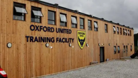 A wooden building with the Oxford United badge and the words "Oxford United Training Centre"