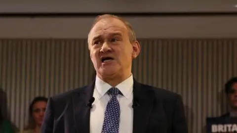 Getty Images Sir Ed Davey in a blue tie and suit delivering his speech 