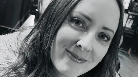 Kirsten Kerr A black and white selfie of Kirsten Kerr, smiling at the camera.