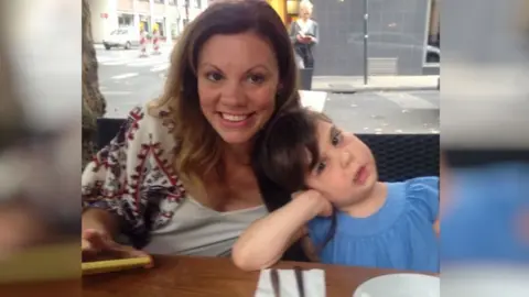 A mother and daughter pose at a restaurant table. 