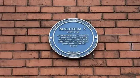 A circular blue plaque honouring Malcolm X.