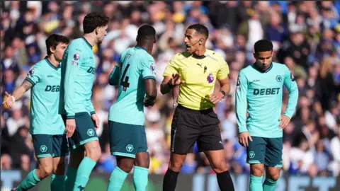 Mike Egerton/PA Wire Wolverhampton Wanderers players speak to referee Farai Hallam before a penalty is awarded to Leeds United during the Premier League match at Elland Road, Leeds. Picture date: Saturday April 18, 2026.