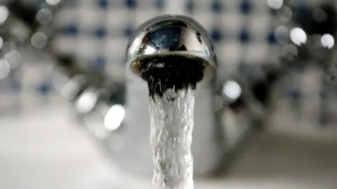 A picture of a tap with water running out of it. It is a silver tap.