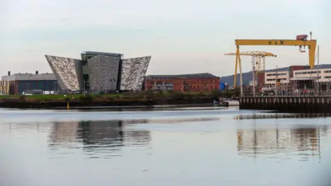 Getty Images The massive silver Titanic Experience building in Belfast. It has many points and is against a blue sky, surrounded by cranes and water.