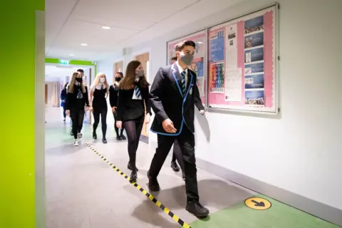 Getty Images Pupils walking through a school observing social distancing measures 