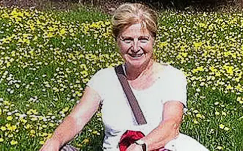 Wiltshire Police Danielle Carr-Gomm pictured wearing a white t-shirt, sat on the ground amongst lots of yellow flowers. 