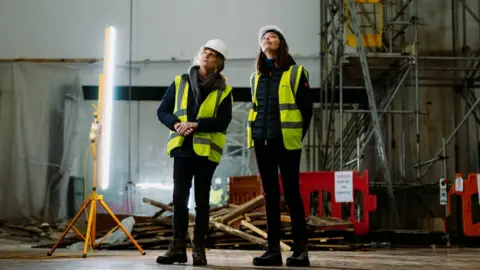 KolabStudios/ AlastairBrookes Jacob Wells Baths building works with two people in high-vis jackets and wearing hard hats inside