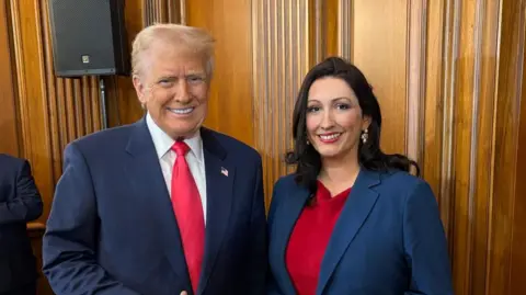 Ni Executive/PA Media Donald Trump gives a thumb as he meets Deputy Minister Emma Little-Pengli. She wore a red dress with blue blazer. The pair are standing in the wooden panel room.