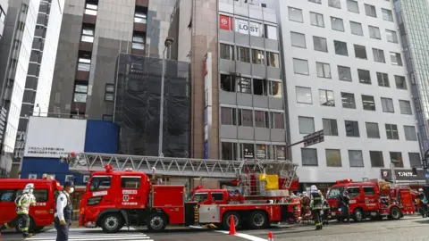 Reuters Fire trucks in front of a building where a blaze broke out in Osaka, western Japan, 17 December 2021