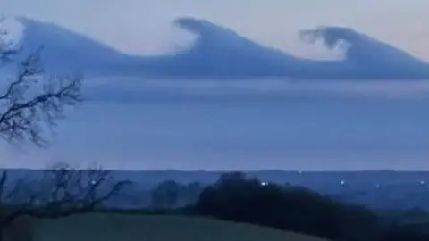 Wave-like cloud formations against a darkening sky
