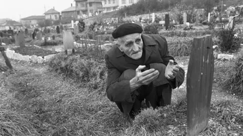 Corbis/Getty Images A father kneels at his son's grave in Sarajevo