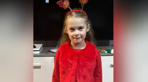 Duaine Davies Amaya Davies smiling in a red outfit.