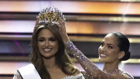 AFP Mia Le Roux (L) is crowned by 2023 Miss South Africa Natasha Joubert (R) on stage at the 2024 Miss South Africa final at SunBet Arena in Pretoria on August 10, 2024.