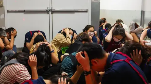 Shoppers and supermarket employees crouch and cover their heads and ears in an underground shelter during an air raid evacuation rehearsal in Taipei
