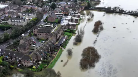 Eddie Mitchell An aerial view over a flooded field next to homes.