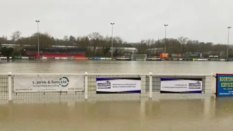 Banbury United Banbury United's ground is submerged by floodwater. The fencing around the pitch stands in the floodwater.