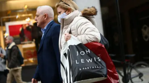 Getty Images Woman carrying John Lewis shopping bag.