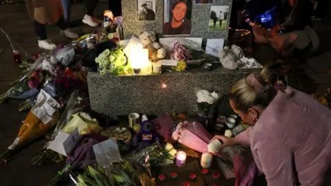 Reuters A woman lights a candle next to flowers and other tributes left for Payne outside St. Peter's collegiate church in Wolverhampton.