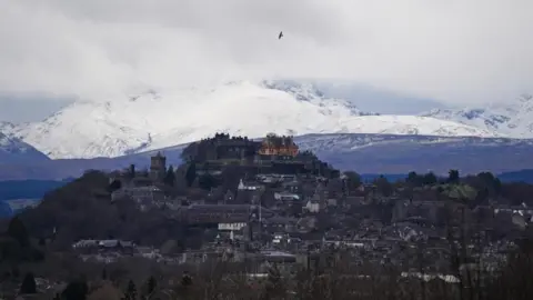 PA Media Stirling castle with Stirling city in the foreground and snow covered mountains in the background.