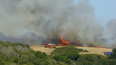 Smoke pluming from a field in Mawgan Porth. There is smoke and flames.
