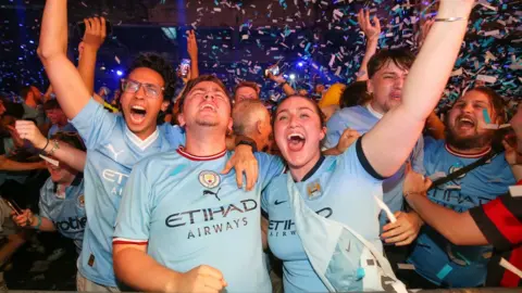 PA Media Manchester City fans celebrate at the Depot Mayfield