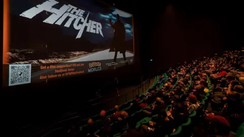 Forbidden Worlds People sit in their seats at the iMax cinema in Bristol to watch The Hitcher as part of a series of horror film screenings as part of the Forbidden Worlds festival. On the screen the opening credits for The Hitcher are visible