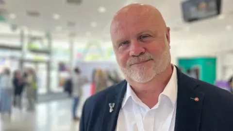 A man in a suit and a white shirt, no tie