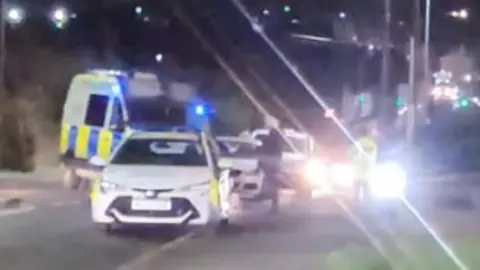 Gary Hurst An image of the police scene, with flashing lights and various police and ambulance vehicles