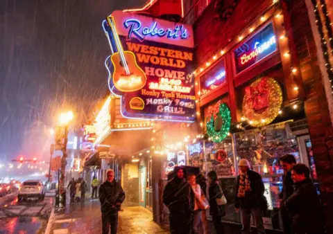 SETH HERALD/AFP Snow falls on Broadway, a popular tourist street in Nashville, Tennessee, on 22 December 2022