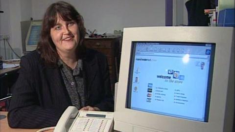 Woman sits beside a computer, with the Manchesternet website on it