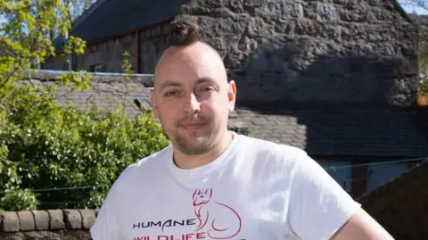 Kevin Newell standing outside wearing a white T-shirt